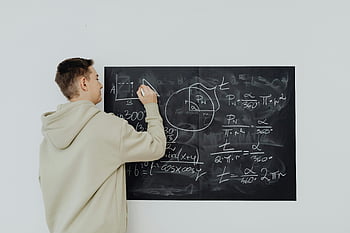 chlapec v béžové mikině, řešení matematického problému, dospívající chlapec, Psaní matematických vzorců, tabule, algebraické rovnice, zaměřený student, vzdělávací scéna, Matematické učení, řešení problémů, Akademická studie