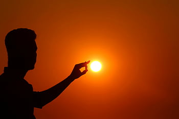 sunset silhouette, man holding sun, dramatic sunset, sunset backdrop, captivating silhouette, sunset photo, silhouette photography, sunset scene, sunset art, sunset image, sunset moment