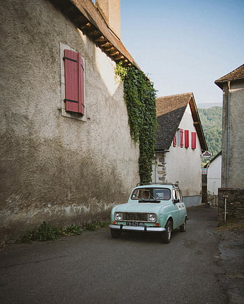 klassisches Auto, europäisches Dorf, malerisches Dorf, malerische Straße, zeitloser Charme, Nostalgie, Oldtimer, geparktes Auto, rote Fensterläden, Efeubewachsene Wand, enge Straße