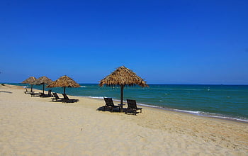 strand, zandstrand, rieten parasols, heldere blauwe zee, zonnige hemel, strandstoelen, kust, rustig strand, strandhuisjes, uitzicht over de oceaan, tropisch strand