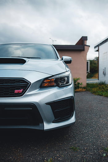 silver Subaru, headlight, front view, sports car, parked outdoors, cloudy day, sleek design, car exterior, automotive photography, vehicle details, Subaru STI