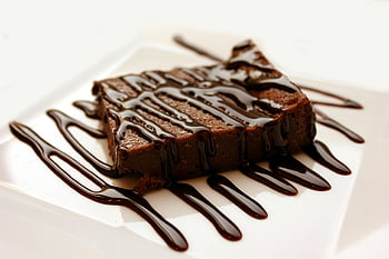 chocolate brownie, melted chocolate, white ceramic plate, dessert lovers, rich chocolate, drizzled syrup, clean white plate, chocolate drizzle, chocolate dessert, brownie dessert, chocolate treat