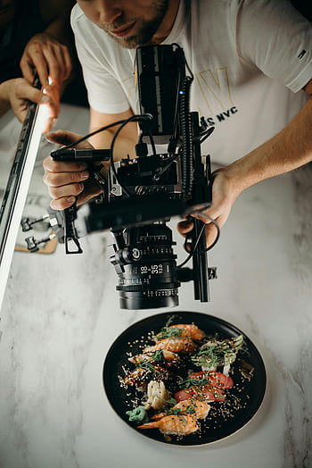 food photography, gourmet dish, high-end camera, above shot, man taking video, professional photographer, food videography, culinary photography, dish capture, food presentation, camera equipment