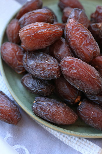 dried dates, candied dates, green ceramic plate, healthy snacking, sweet dried dates, close-up dates, dried fruit, snack food, natural sweets, date fruit, green plate