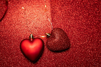 red heart decoration, shiny surface, heart-shaped ornaments, glittering red surface, Valentine's Day décor, romantic decor, festive hearts, holiday decoration, love symbol, sparkling background, romantic theme