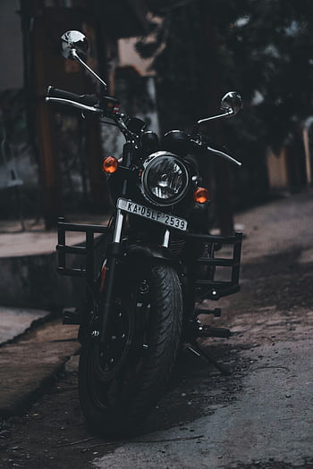 black motorcycle, parked motorcycle, street, moody lighting, vertical photo, outdoor, urban scene, license plate, front view, handlebars, tires