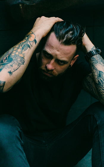 tattooed man, black t-shirt, dark setting, moody, artistic vibe, thoughtful pose, tattoos, artistic photography, dark photography, man posing, moody portrait