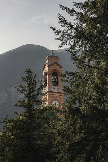 Bell Tower, Green Trees, Lombardy, Italy, Scenic View, Surrounding Trees, Mountain Background, Architectural Landmark, Clock Tower, European Landscape, Nature Scene