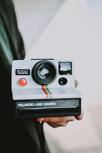 Polaroid Land Camera, retro camera, vintage photography, close-up camera, person holding camera, Polaroid 1000, vintage style, instant camera, photography style, retro Polaroid, vintage camera