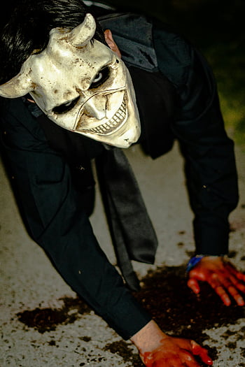 creepy person, skull mask, frightening masked figure, horns, crawling on ground, horror themes, scary, Halloween, horror photography, spooky, blood-stained hands