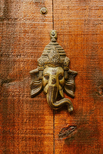 Ganesha, door knocker, ornate, rustic wooden door, Hindu, religious art, close-up, Ganesha head, symbolic, traditional, decoration