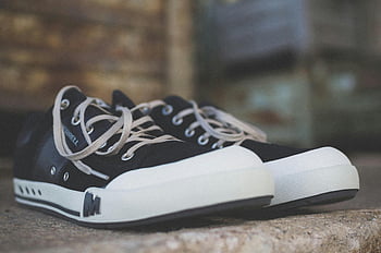 schwarze Low-Top-Sneaker, Gelegenheits -Turnschuhe, Schwarz -Weiß -Turnschuhe, klassischer Stil, rustikale Steinoberfläche, Paar von Turnschuhen, Niedrige Schuhe, Freizeitschuhe, schwarze Turnschuhe, weiße Sohlen, klassische Sneaker