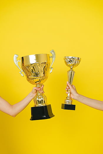 trofeum, ręce trzymające trofea, żółte tło, Symbol sukcesu, złote trofeum, nagroda, zwycięstwo, osiągnięcie, zawody, uroczystość, zwycięzcy