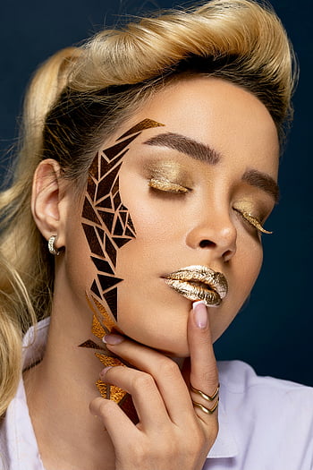 Goldenes Make -up, Geometrische Gesichtskunst, Studioportrait, schimmerndes Make -up, Frau, Gesicht Kunst, Goldener Lippenstift, kompliziertes Make -up, Modell-, Studioaufnahme, Portraitfotografie