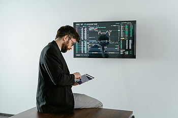 黒いジャケットの男、 デジタルタブレット、 金融グラフ、 株式市場スクリーン、 若者、 オフィス設定、 データ分析、 ビジネス分析、 財務分析、 タブレットの使用、 株式市場の表示