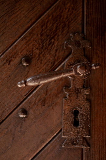 vintage metal keyhole, heavy wooden door, intricate vintage door handle, textured wooden door, classic design, close-up, antique hardware, rustic door, old-fashioned lock, vintage door, metal handle