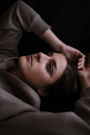 woman crying, close-up, tears, lying down, deep emotion, emotional portrait, sad woman, facial expression, black background, emotional photography, woman in tears