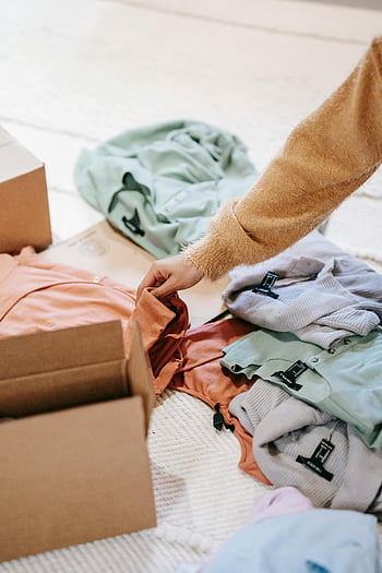 faceless lady, packing clothes, cardboard boxes, indoor room, colorful clothes, serene home, organizing clothes, floor packing, home atmosphere, indoor organization, clothing storage