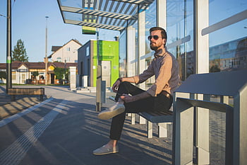 uomo che indossa occhiali da sole, fermata dell'autobus, giorno, uomo alla moda, fermata dell'autobus contemporanea, all'aperto, illuminata dal sole, Abbigliamento casual, contesto urbano, architettura moderna, scena di strada