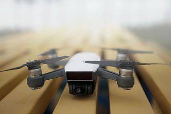 white quadcopter, gray drone, shallow focus photography, close-up drone, wooden surface, technology enthusiasts, sleek drone, white drone, quadcopter close-up, drone photography, quadcopter details