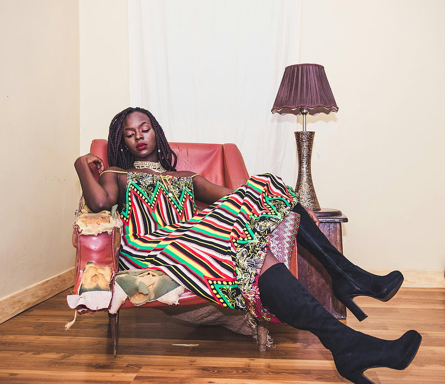 woman sitting on chair, fashionable woman, colorful dress, vintage chair, indoors, stylish outfit, black boots, elegant pose, home decor, lamp, wooden floor