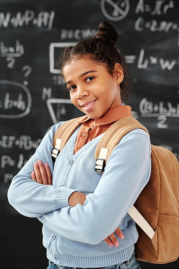 schoolgirl, blue long sleeve shirt, brown leather backpack, smiling, confident pose, classroom chalkboard, math equations, education, student, back to school, school uniform