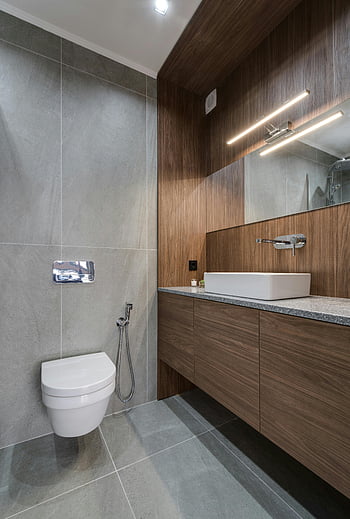 modernes Badezimmer, Toilette, Schlanke Spiele, Holzakzente, modernes Design, stilvolles Badezimmer, zeitgemäßes Design, Badezimmerarmaturen, Holzschränke, Badezimmereitelkeit, Wandmontierte Toilette
