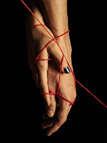 hands with red thread, conceptual portrait, artistic portrayal, connection and unity, entwined hands, red thread symbol, black background, nail polish, intimate connection, symbolic art, hand art