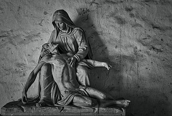 religious stone sculpture, black and white photo, Pieta sculpture, Jesus Christ, Mary, solemn religious context, stone statue, religious art, monochrome image, religious iconography, sculpture art