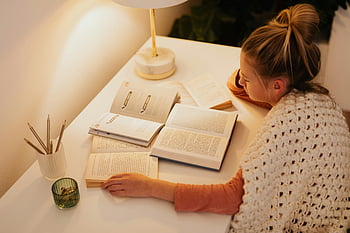 vrouw lezen, meerdere boeken, warm verlichte bureau, rustige avond, gezellige sfeer, bureaulamp, open boeken, Lezen Nook, Comfortabel lezen, gerichte lezing, vredige omgeving