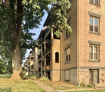 Martanna Flats, Mission Revival, brick building, tree shaded lawn, triple decker porches, red tile roof, historic district, Covington Kentucky, Wallace Woods, stone base, tuscan columns