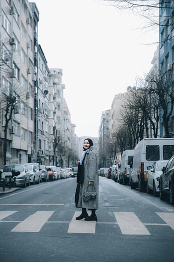 woman, zebra crossing, winter clothing, city street, urban buildings, crossing street, winter coat, cityscape, pedestrian, urban environment, winter fashion