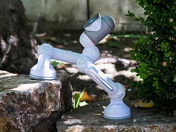 White and Blue ClicBot, concrete surface, modern robot, climbing stone steps, advanced robotics technology, outdoor setting, small robot, robotic technology, outdoor robotics, stone steps, modern robotics
