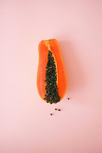 papaya, cut papaya, ripe papaya, exotic fruit, pink surface, vibrant papaya, halved papaya, pastel pink backdrop, papaya seeds, tropical fruit, fruit photography