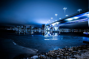 bro med lys om natten, levende blå bybilde, Moderne opplyst bro, rolig vann, natt scene, byens skyline, urbane landskap, nattfotografering, brorefleksjon, utsikt mot sjøen, gatelys