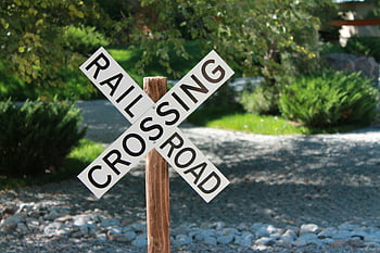 railroad crossing, road sign, close-up, outdoor, gravel path, greenery, wooden post, safety sign, warning sign, transportation, landscape