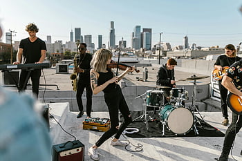 woman playing violin, rooftop performance, live band, city skyline, outdoor concert, musical instruments, urban music scene, rooftop event, cityscape background, band performance, violinist