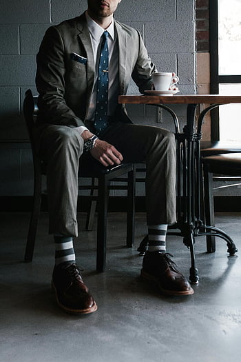 man sitting on chair, designer suit, coffee, chic cafe, stylish outfit, formal attire, striped socks, leather shoes, watch, modern setting, elegant man