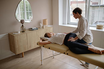 massage therapy, woman in white shirt, black leggings, therapy bed, serene room, well-lit room, calming massage, massage table, therapist, relaxation, indoor setting