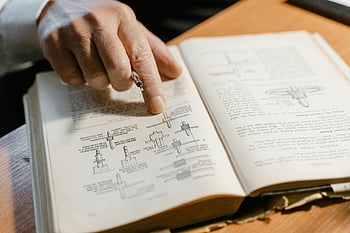 finger pointing, page in book, engineering concepts, hand pointing, diagram in book, learning, open book, educational content, study materials, technical diagrams, academic study