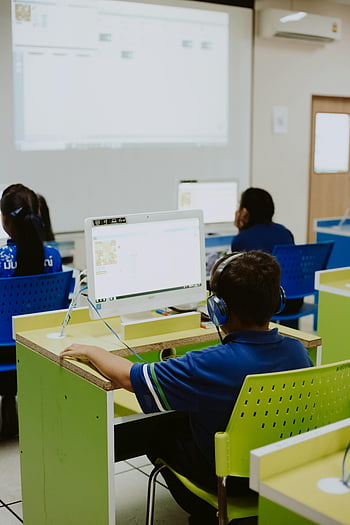 students using computers, children learning, computer lab, classroom setting, educational technology, kids on computers, school computers, computer education, student engagement, learning environment, headphones