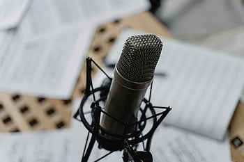 condenser microphone, studio microphone, close-up photography, music sheets, mic stand, recording studio, audio equipment, professional microphone, studio setting, music recording, sound recording