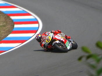 motorkerékpár versenyző, piros motorkerékpárruhák, piros és zöld sportos motorkerékpár, nagy sebességű pálya, éles görbe, verseny, motorkerékpár, sebesség, versenypálya, sport motorkerékpár