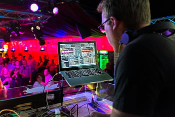 DJ, laptop, nightclub, vibrant crowd, colorful lighting, music, lively, headphones, table, performance, event