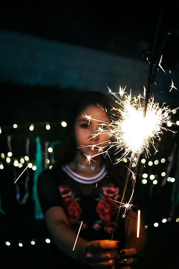 donna che tiene sparkler, Sparkler notturna, Atmosfera festosa, luci scintillanti, Sparkler luminoso, Ragazza con Sparkler, scena notturna, notte festiva, Sparkler Glow, Celebrazione all'aperto, celebrazione notturna