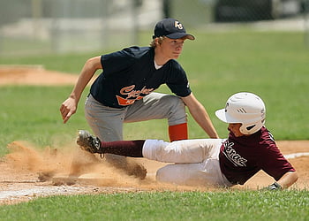 youth baseball game, sliding player, tagging player, base, action moment, young players, baseball field, sports action, competitive play, dust cloud, excitement