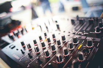 audio mixer, DJ mixing panel, knobs, sliders, close-up shot, blurred background, black and gray, music equipment, sound control, studio gear, audio production