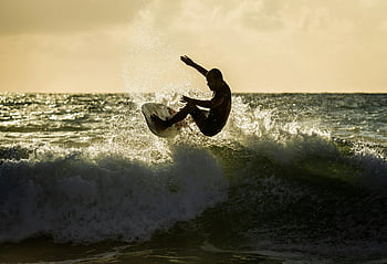 Surfen, Surfer, Welle, Sonnenuntergang, Ozean, Dynamischer Schuss, geschickter Reiten, atemberaubende Kulisse, Strandszene, Wassersport, Action-Schuss