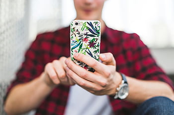 person holding phone, multicolored floral case, vibrant floral case, smartphone case, close-up image, person holding smartphone, floral phone case, colorful phone case, smartphone with case, floral design, vibrant design