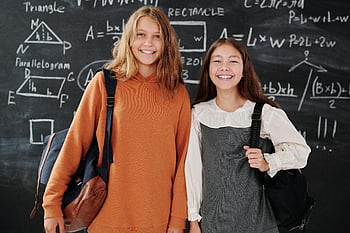 girls smiling, camera, students, backpacks, chalkboard, math formulas, school, education, classroom, learning, friends
